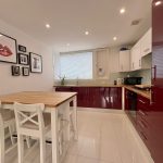 Modern kitchen with red cabinets and dining table.