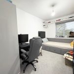 Cosy bedroom with desk, bed, and shelves.