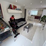 Modern living room with pinball machine and plants.