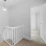 Bright hallway with white staircase and bathroom.