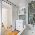 Modern bathroom with green tiles and white fixtures.