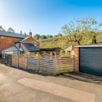 Charming cottage with driveway and garage under blue sky.