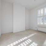Empty room with white walls and shuttered window.