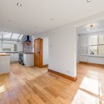 Bright open-plan kitchen and living area with wooden floor.