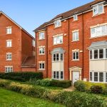 Red brick apartment building with green lawn.