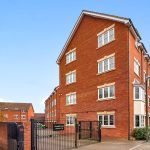 Modern red brick apartment building with gated entry