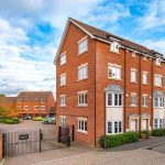 Modern red-brick apartment building with gated entrance.