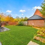 Back garden with autumn leaves and brick garage.