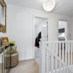 Modern upstairs hallway with decorative mirror and railings.