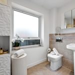 Modern bathroom with sink, toilet, and window.