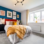 Modern bedroom with blue accent wall and artwork.
