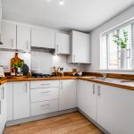 Modern kitchen with wooden countertops and white cabinets.