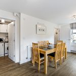 Modern dining room with wooden furniture and kitchen.