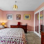 Cosy bedroom with pink walls and artwork.