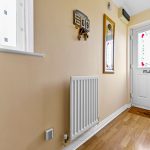 Hallway with radiator, wall calendar, and glass door.