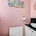 Pink bathroom with white sink and artwork