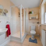 Modern bathroom with shower, toilet, and towel rack.