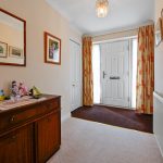Cosy hallway with wooden sideboard and white door.