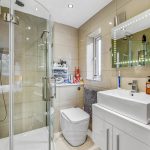 Modern bathroom with shower, sink, and storage.