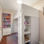 Small room with loft bed and bookcase.