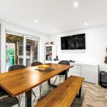 Modern dining room with large table and TV.