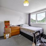 Cosy bedroom with bed, boxes, and natural light.