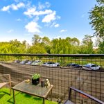 Balcony view with trees and parked cars.