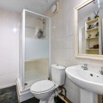 Compact bathroom with shower, toilet, and sink.