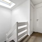 White hallway with skylight and closed door.