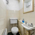 Compact bathroom with toilet, sink, and mirror.