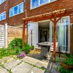 Sunny backyard with pergola and barbecue grill.
