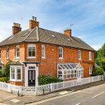 Corner red brick house with white picket fence.