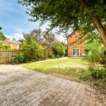 Spacious garden with trees and brick house.