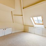Bright attic room with skylight and storage cupboards.