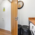 Laundry room with wooden door and bathroom view.