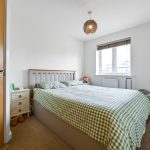 Bright bedroom with checkered bedding, window and lamp.