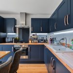Modern navy kitchen with wooden worktops and appliances.