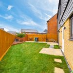 Sunny backyard with patio furniture and grass garden.