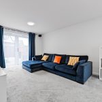 Bright living room with blue sofa and colourful cushions.