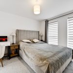 Modern bedroom with grey decor and desk.