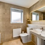 Modern bathroom with bathtub, sink, and illuminated mirror.