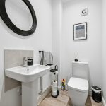 Minimalist modern white bathroom with round mirror.