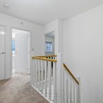 White hallway with doors and staircase