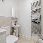 Modern bathroom with sink, toilet, and towel radiator.