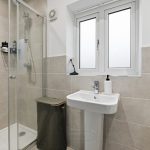 Modern bathroom with shower, sink, and window.
