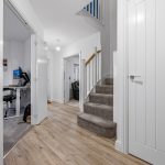 Modern hallway with open doors and carpeted stairs.