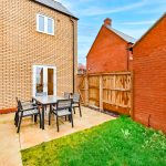 Back garden with table and chairs on patio.