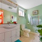 Modern bathroom with green walls and plants.