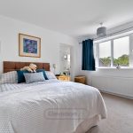 Bright bedroom with double bed and blue curtains.