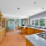 Spacious modern kitchen with wooden cabinets and large windows.